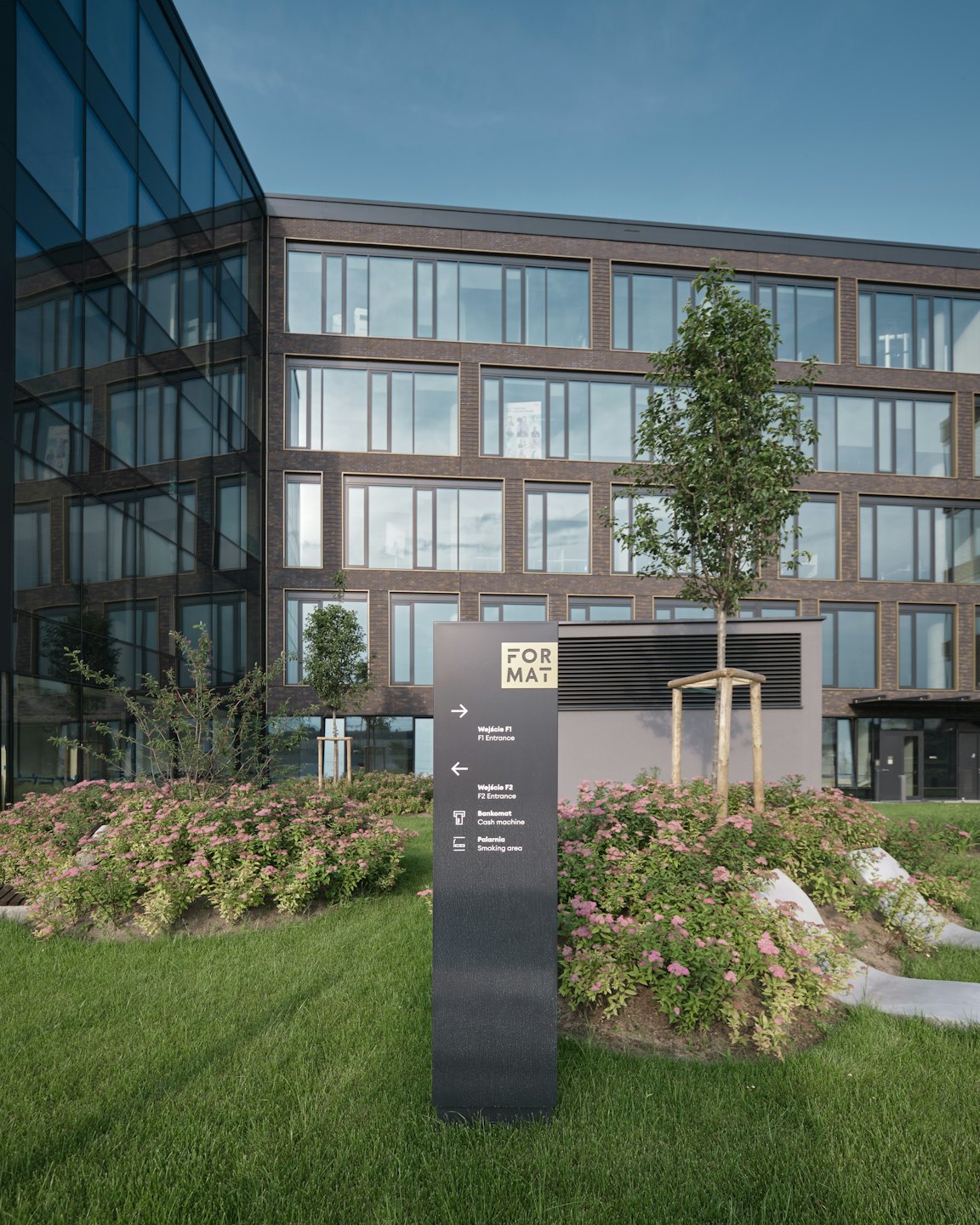 Moderno edificio per uffici con un cartello direzionale in una giornata di sole.